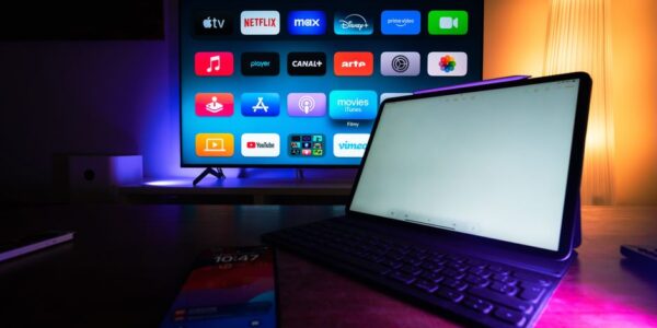 Telewizor z menu aplikacji streamingowych oraz tablet i smartfon na stole