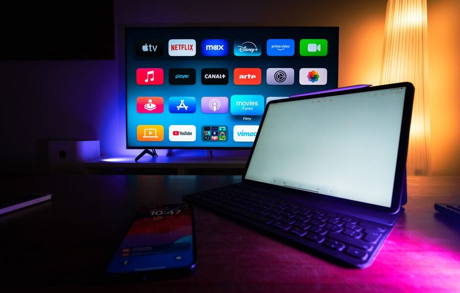 Telewizor z menu aplikacji streamingowych oraz tablet i smartfon na stole