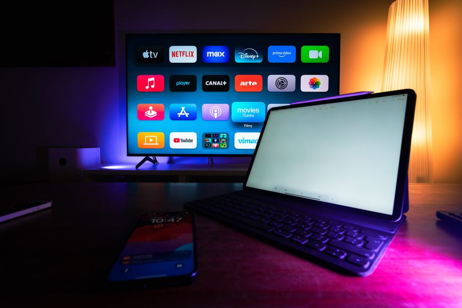 Telewizor z menu aplikacji streamingowych oraz tablet i smartfon na stole